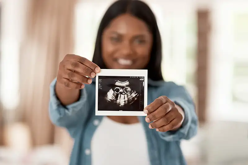 Gestational carrier holding an ultrasound image, representing transparency, respect, and support in surrogate compensation